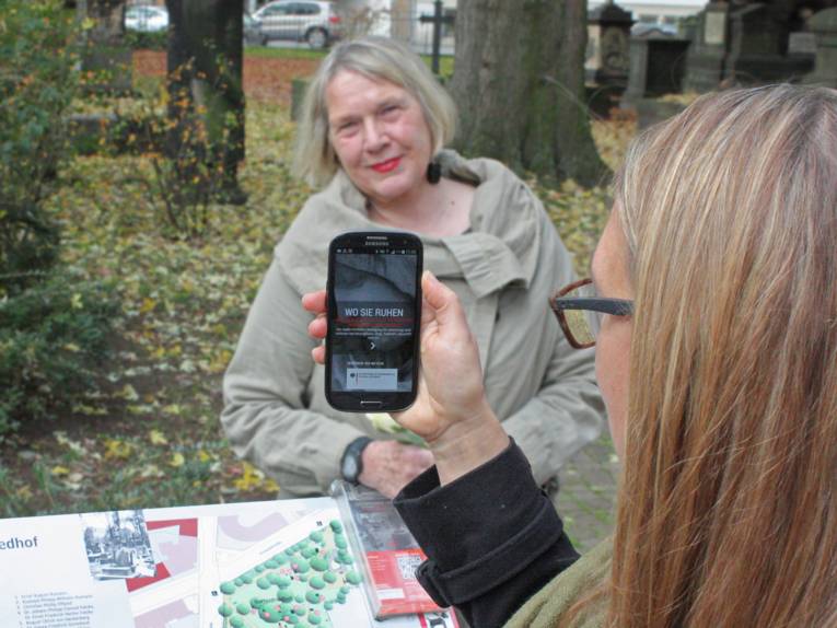 Eine Frau zeigt auf ihrem Smartphone eine Internetseite